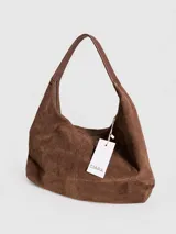 Cartera tipo hobo de diseño relajado, confeccionada en material con textura simil gamuza color chocolate. Presenta una silueta suave, cierre superior y asa corta combinada en simil cuero al tono.
