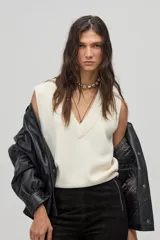 Chaleco tejido color crema con escote en V y terminaciones de rib.