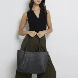 Set de cartera tipo tote y bolso de mano Guess, color negro con estampado de logo de la marca. Ambos cuentan con diseño estructurado, cierre superior y logo metálico frontal.
