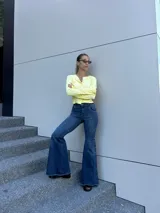 Jean de corte oxford y tiro medio, confeccionado en denim elastizado. Presenta recortes curvos en las piernas y detalle de botones laterales en la botamanga con terminación desflecada.