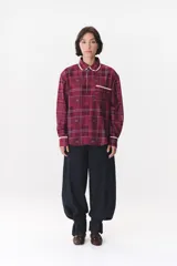 Camisa de corte holgado en color bordó con estampado de cuadros y monograma. Presenta cuello redondo con borde de puntilla, bolsillo frontal con detalle de puntilla, cierre frontal con botones y puños con terminación en puntilla.