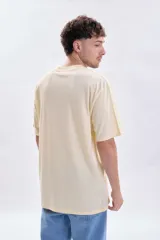 Remera de corte oversize color amarillo claro, con cuello redondo y estampa minimalista en el centro del pecho.