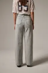 Pantalón jean de tiro alto y corte recto, confeccionado en denim celeste con aplicación de strass en toda la parte frontal.