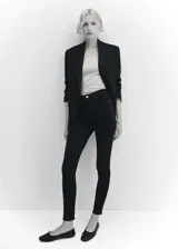 Jeans skinny de tiro alto en color negro, con diseño de cinco bolsillos, trabillas para cinturón y cierre frontal con cremallera y botón.