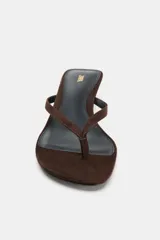 Sandalia tipo chinela de ante color marrón oscuro, con tacón kitten bajo y fino. Posee dos tiras finas en la parte delantera, una de ellas con separación para el dedo pulgar.
