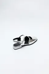 Zuecos destalonados color crema, de símil cuero, con punta cuadrada y finas tiras con hebillas ajustables. Cuentan con taco de 2,5cm de alto.