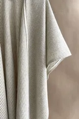 Ruana de lana fina color crudo con terminación envivada.