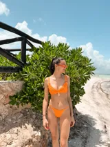 Top de bikini con aros, confeccionado en tela brillante color azul oscuro. Presenta breteles regulables con argollas decorativas y cierre mediante atado en la espalda.