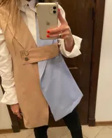 Chaleco corto sin mangas, con solapas y diseño color block en blanco y negro. Presenta un cinturón ancho con hebilla dorada.