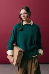 Buzo de tejido de punto color verde esmeralda, con cuello redondo a la base, mangas largas y puños acanalados. Presenta una silueta ligeramente oversize.