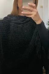 Poncho tejido de lana merino color negro con cuello alto y flecos en el ruedo.