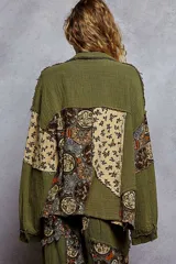 Camisa de manga larga con diseño patchwork en tonos verde militar y beige. Presenta un estampado floral pequeño en las secciones beige y un tejido texturizado en las secciones verdes. Tiene cuello camisero y botones frontales.