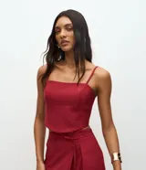 Blusa de sastrería color bordó, con escote recto, breteles finos ajustables y diseño estructurado con recortes que moldean el busto. Cuenta con cierre de cremallera en la espalda.