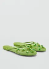 Zapato tipo mule destalonado de color verde, confeccionado en tejido de malla con diseño de rejilla. Presenta punta redonda y está decorado con abalorios y aplicaciones brillantes en la parte superior.