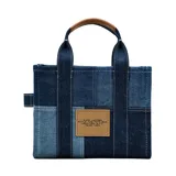 Cartera tipo tote bag de Marc Jacobs, confeccionada en denim con diseño de paneles en diferentes tonos de azul. Presenta el logo estampado en el frente, doble asa superior y correa de hombro ajustable y extraíble.