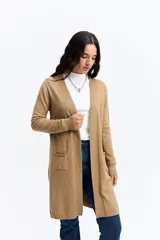 Saco tipo cárdigan largo de punto, color beige, con frente abierto, mangas largas con puños acanalados y bolsillos frontales aplicados.