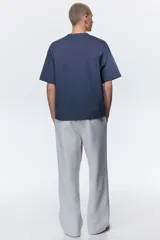 Pantalón deportivo en felpa pesada de mezcla de algodón, color gris claro, de corte holgado con cintura elástica ajustable mediante cordón y bolsillos laterales.