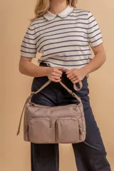 Bandolera de tafeta impermeable color beige, con dos bolsillos frontales con cierre y correa regulable. Diseño práctico y liviano ideal para uso diario.