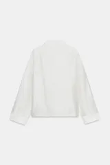 Camisa de estilo oriental confeccionada en mezcla de lyocell con acabado satinado. Presenta cuello redondo, manga larga con puños rectos, bolsillos de plastrón y cierre frontal mediante alamares.