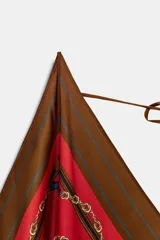 Top de escote pico y tirantes finos, con lazada en la espalda y bajo asimétrico. Presenta un estampado de cadenas y rayas en tonos rojos, azules y marrones.