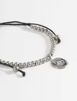Pulsera ajustable de cordón negro con cuentas metálicas plateadas y un dije circular de acero con diseño de estrella grabada.
