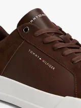 Zapatillas de corte bajo Tommy Hilfiger confeccionadas en una combinación de piel nobuk y piel lisa en color marrón. Presentan suela de goma blanca, detalle de ventilación lateral, logo de la marca en la lengüeta, lateral y talón, y cierre mediante cordones.
