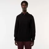 Remera de manga larga negra con cuello polo y tapeta de dos botones. Presenta un tejido de punto de fantasía con textura de pequeños puntos.