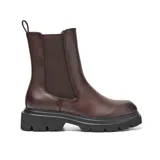 Bota tipo Chelsea de caña media en color marrón, confeccionada en material sintético con acabado liso. Presenta paneles laterales elásticos, tirador trasero y una suela chunky de goma negra con plataforma dentada.