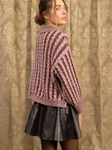 Sweater de punto con diseño de trenzas verticales, cuello alto y corte holgado. Presenta mangas largas con puños acanalados y un largo a la cadera.