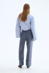 Pantalón sastrero de sarga color azul, de corte recto y pierna ancha, con pliegues frontales y doblez ancho en los bajos.