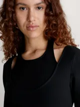 Vestido corto negro de punto milano con top de doble capa que crea un efecto recortado y con volumen. Tiene cuello abierto bajo, top interno fijo de cuello halter, efecto recortado en el hombro, manga larga y cremallera lateral oculta.