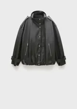 Anorak de diseño oversize en color negro, con cuello alto, cierre frontal de botones y cremallera oculta bajo tapeta. Presenta mangas largas con puños de tira abotonada, bolsillos laterales con cremallera y detalles de charreteras en los hombros.
