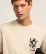 Remera color crema de algodón con cuello redondo y mangas cortas. Estampa trasera con un dragón oriental en tonos negros y rojos.