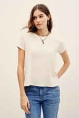 Remera básica de corte holgado, color negro, con mangas cortas y cuello redondo. Presenta un diseño con largo irregular y ruedo redondeado, confeccionada en algodón peruano con textura jaspeada.