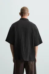 Camisa de manga corta con cuello solapa, confeccionada en tejido de mezcla de lyocell con textura de efecto arrugado y cierre frontal de botones.