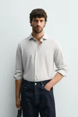 Camisa regular fit de manga larga con diseño de rayas verticales celestes y blancas, cuello italiano y cierre frontal con botones.
