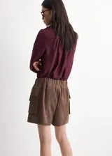 Blusa de manga larga bordó con cuello alto y detalle de fular integrado para anudar al cuello, corte recto y puños abotonados.