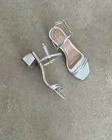 Sandalias de tacón bajo color blanco, con tiras finas y cierre con hebilla.