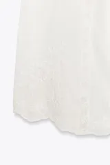 Top blanco de escote recto y tirantes finos, con detalle de flores bordadas y frunces.