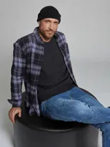 Camisa de franela de manga larga con diseño de cuadros en tonos violeta y negro, confeccionada en algodón. Presenta cuello clásico y cierre frontal con botones.