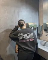 Buzo negro de cuello redondo y manga larga, de corte regular fit. En la espalda presenta un estampado gráfico en color blanco y rosa con la leyenda "Fletes" y el dibujo de una grúa transportando una planta.