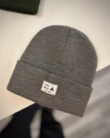 Gorro de lana gris con etiqueta de tela con logo de la marca en el frente.