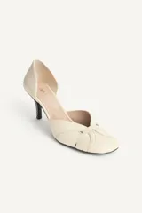 Zapato de tacón de piel color beige, con detalle cruzado en la parte delantera y tacón alto fino combinado con acabado en punta redonda.