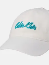Gorra de sarga de algodón en color blanco, con visera curva y logo de Calvin Klein bordado en color turquesa en la parte frontal. Cuenta con cierre metálico ajustable en la parte posterior.