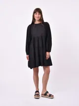 Vestido corto negro con escote redondo, mangas largas abullonadas y falda de tres volados.