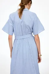 Vestido midi con diseño a rayas en tonos azul y blanco, cuello camisero, botonadura frontal y mangas raglán cortas. Cuenta con elástico fino en la parte posterior de la cintura y tira para atar extraíble.