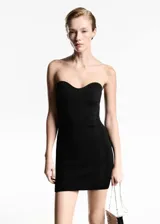Vestido corto de punto acanalado en color negro, con diseño strapless y escote corazón. Presenta un corte entallado al cuerpo.