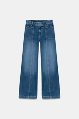 Jeans de tiro alto con corte culotte y pernera ancha. Presenta bolsillos de plastrón en el frente con detalle de pespuntes decorativos en forma de onda y costuras verticales a lo largo de la pierna. Cierre frontal con cremallera y botón metálico.