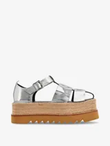 Sandalias plateadas de cuero con plataforma de yute y suela de goma. Tiras anchas cruzadas en el empeine y tira con hebilla al tobillo.