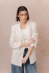 Blazer de lino color beige, de corte recto y líneas clásicas. Presenta solapa clásica, cierre frontal con un botón y bolsillos delanteros con tapa.